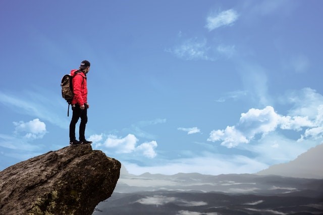 A person standing on the top of a cliff looking at a distance.