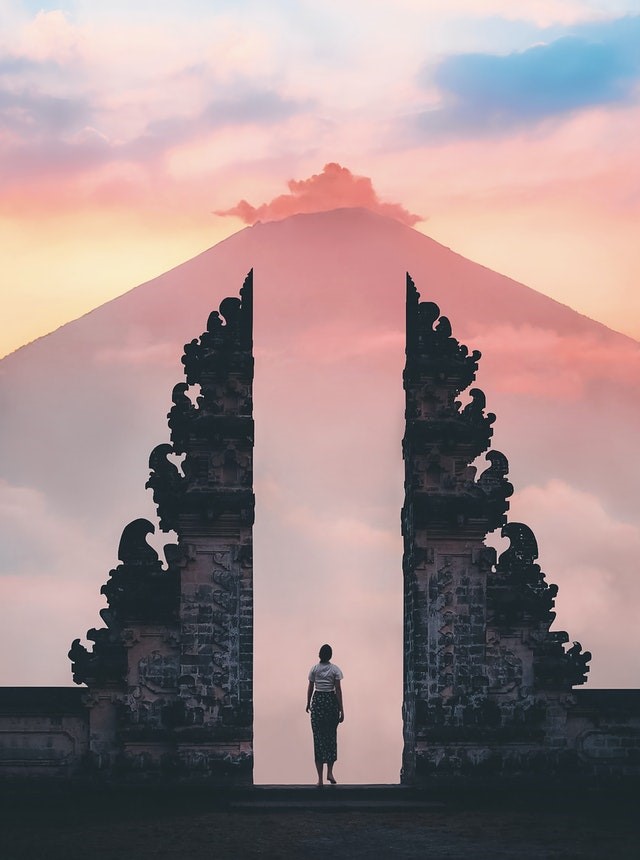 a woman standing between a gate made of rock