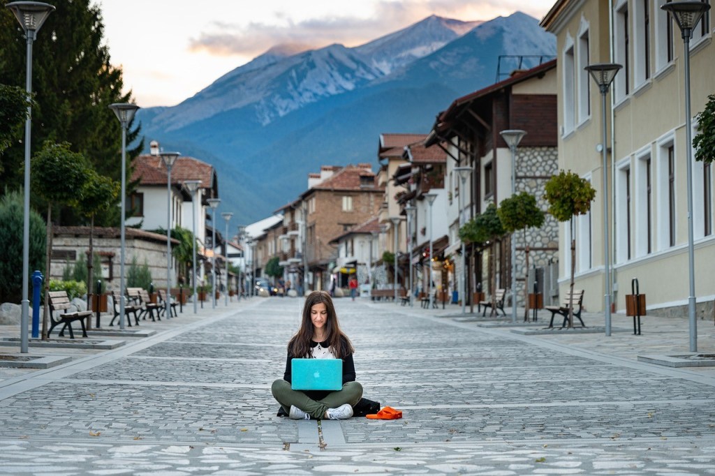 A woman working on a laptop in the middle of a street