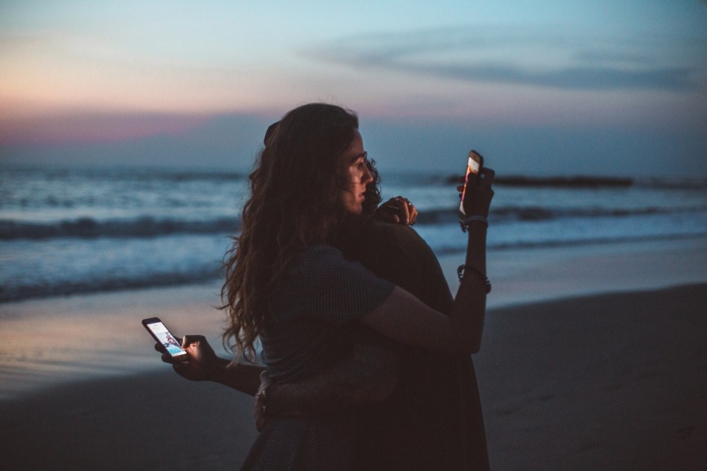 Two people hugging each other while posting on social media