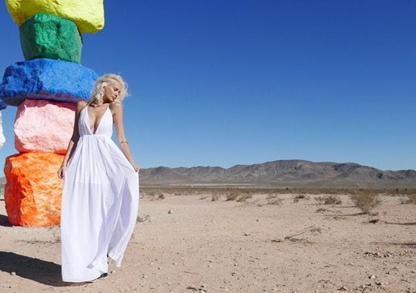 Woman in white dress posing in front of colorful rock formations
