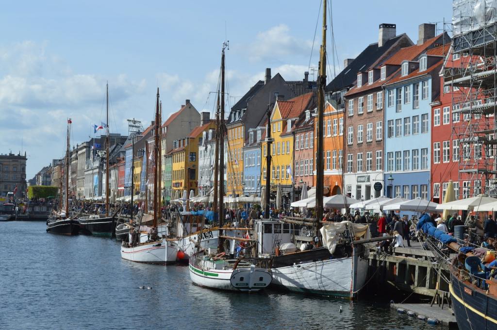 The view of colorful buildings next to the river where there are several boats.