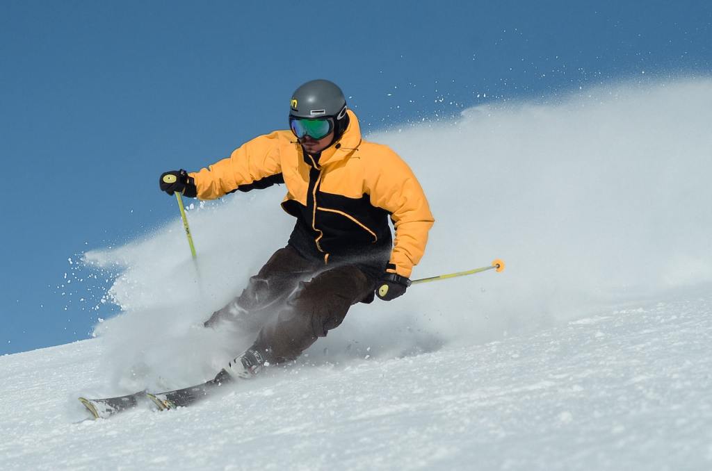A man in black and orange jacket skiing