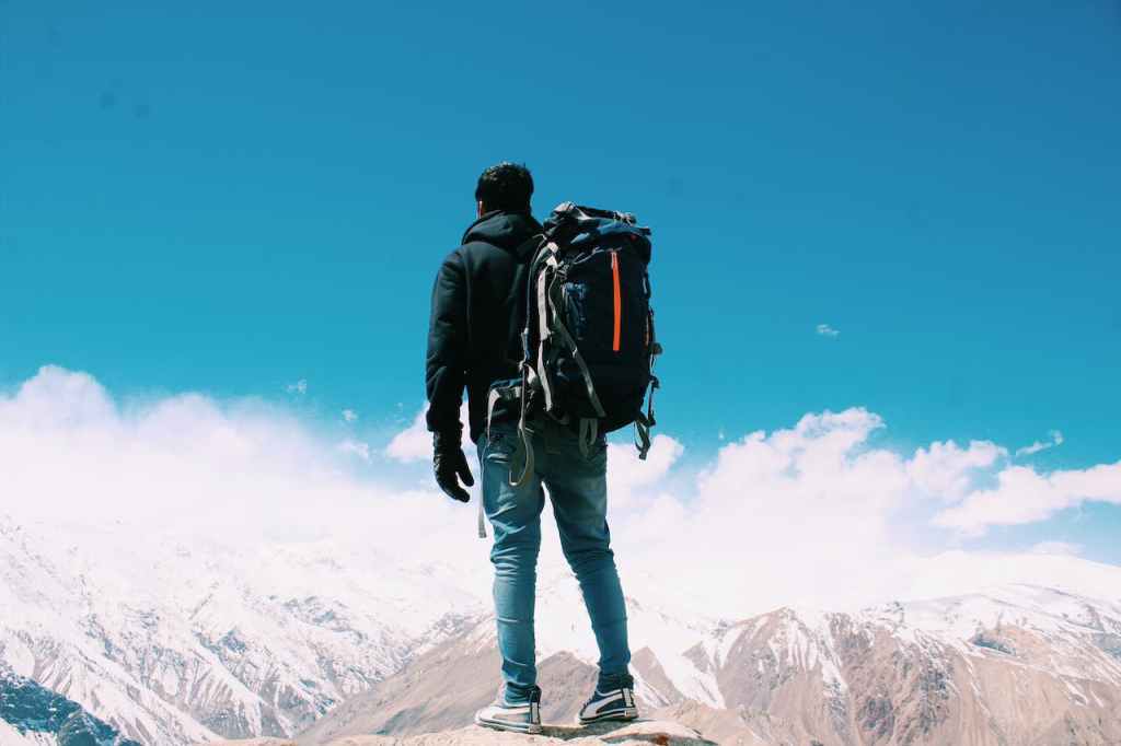 A man with a backpack is standing on a mountaintop