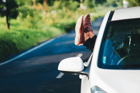 A person holding their feet out a car window