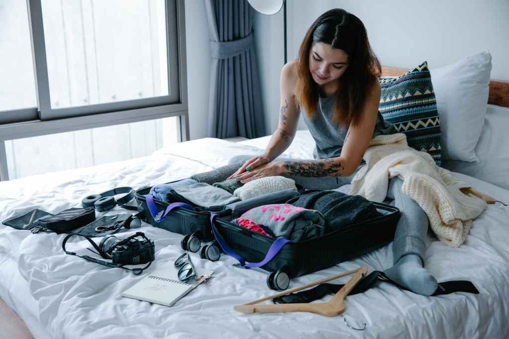 woman packing must-have packing essentials in a suitcase