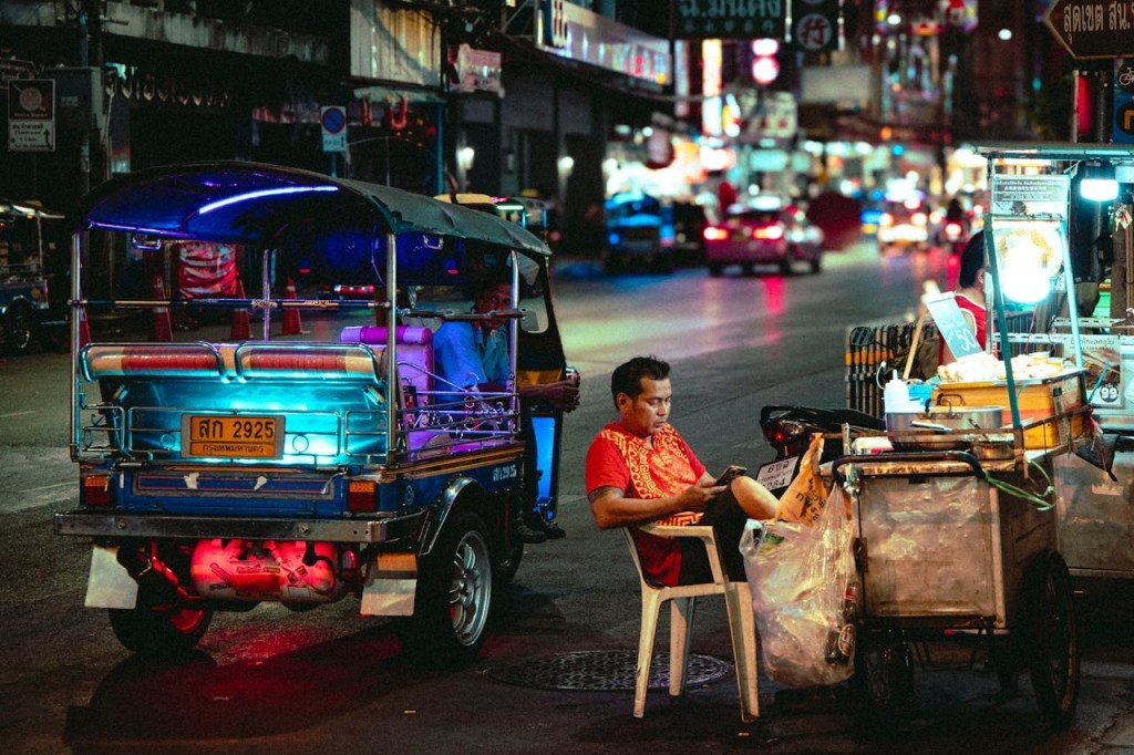a man sittiing beside a street in Thailand